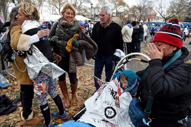 Runner Erin McCloskey (left ) is hugged by her mother, Carol after pushing Kerry Gruson (in racing wheelchair) in thePhiladelphia Marathon. Also meeting them on Eakins Oval is Erin's father, James (rear, right) and her co-worker, Maria Cilluffo (rear, center). Wiping tears at right is caretaker Clara Alarcon.