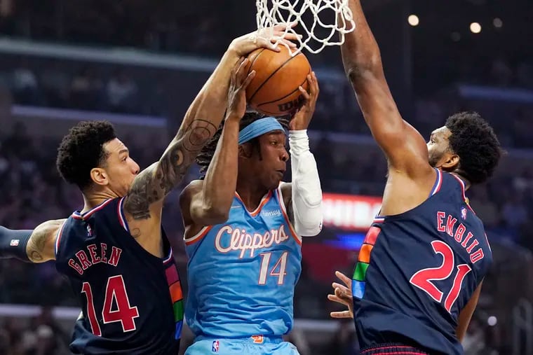 Los Angeles Clippers guard Terance Mann (center) tries to pass the ball while under pressure from 76ers forward Danny Green (left) and center Joel Embiid during the first half of their game on Friday, March 25, 2022, in Los Angeles.
