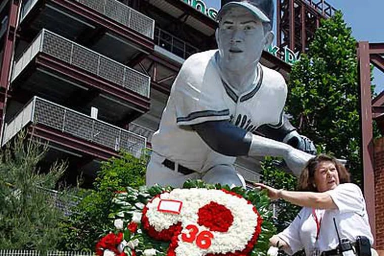 Chris Long with the Phillies adjusts a flower arrangement at the statue of Robin Roberts. (AP Photo/Matt Slocum)