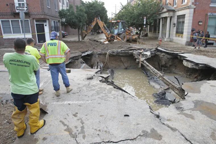 Officials say they won’t know for several weeks what caused a water main beneath 21st and Bainbridge Streets to rupture Sunday. (ALEJANDRO A. ALVAREZ / Staff Photographer)