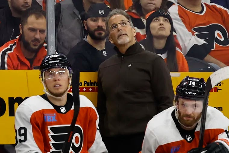 Flyers coach John Tortorella watches a replay on the big screen with players right wing Cam Atkinson (left) and center Sean Couturier on Saturday.