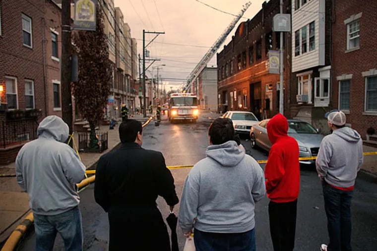 Members of the Fralinger String Band watch as firefighters deal with the aftermath of Monday's blaze at a South Philly warehouse that housed their props and floats. (Alejandro A. Alvarez/Staff)