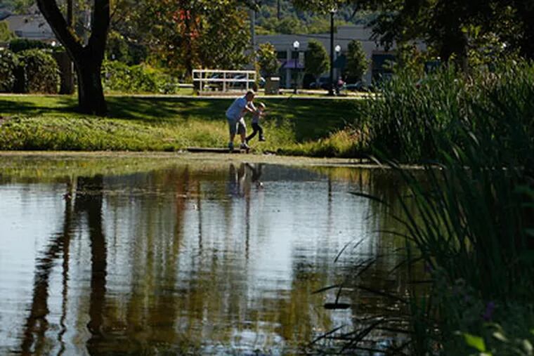 Doug Rider Sr. picks up his grandson, Max Rider, while enjoying time with other family who were fishing at the pond in Kardon Park last year. (Ron Cortes / Staff Photographer)