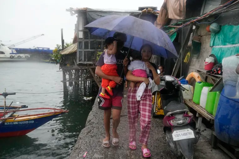 Residents carry their children as they evacuate to safer grounds to prepare for the coming of Typhoon Noru at the seaside slum district of Tondo in Manila, Philippines, Sunday, Sept. 25, 2022. The powerful typhoon shifted and abruptly gained strength in an "explosive intensification" Sunday as it blew closer to the northeastern Philippines.