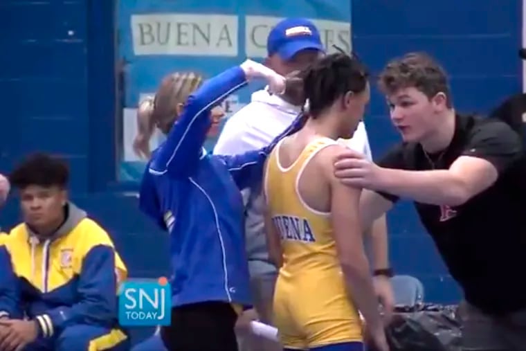 In this image taken from a Wednesday, Dec. 19, 2018 video provided by SNJTODAY.COM, Buena Regional High School wrestler Andrew Johnson gets his dreadlocks cut courtside minutes before his match in Buena, N.J., after a referee told Johnson he would forfeit his bout without a hair covering. The referee, Alan Maloney, has been suspended pending an investigation by the New Jersey Division on Civil Rights. (Michael Frankel/SNJTODAY.COM viavAP)