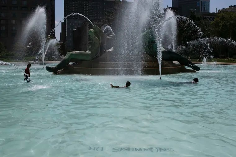 A “No Swimming” sign is seen inside the Swann Memorial Fountain in Logan Square as people swim in the fountain on Tuesday, July 30, 2019. Despite the rules, the fountain is a popular spot for swimming on hot summer days.