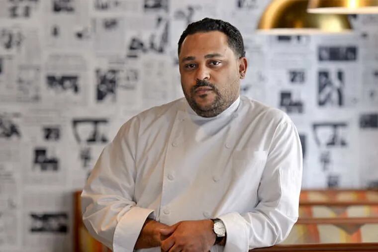 Chef and owner Kevin Sbraga in the dining room of Juniper Commons on South Broad Street. Old newspaper front pages, along with old album covers, cover the walls of the retro restaurant. ( Tom Gralish / Staff Photographer )