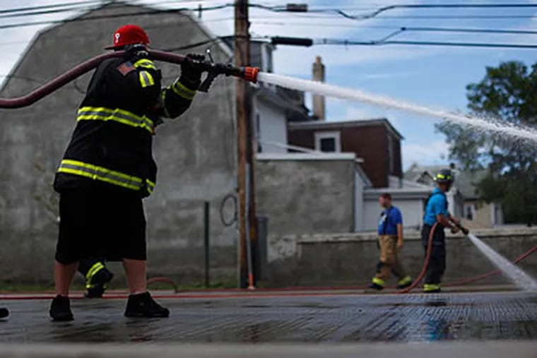 Firefighters spray away the mud in the aftermath of a flood  in Darby on Friday. (AP Photo / Matt Rourke)