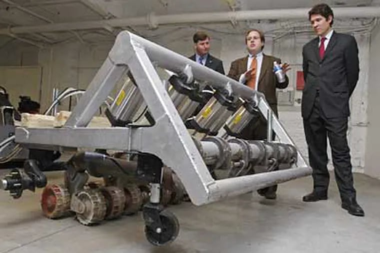 U.S. Rep. Patrick J. Murphy (left) listens to Joshua Koplin (center) and Samuel Reeves, of Humanistic Robotics, Inc., explain how their robotic minesweeper works.