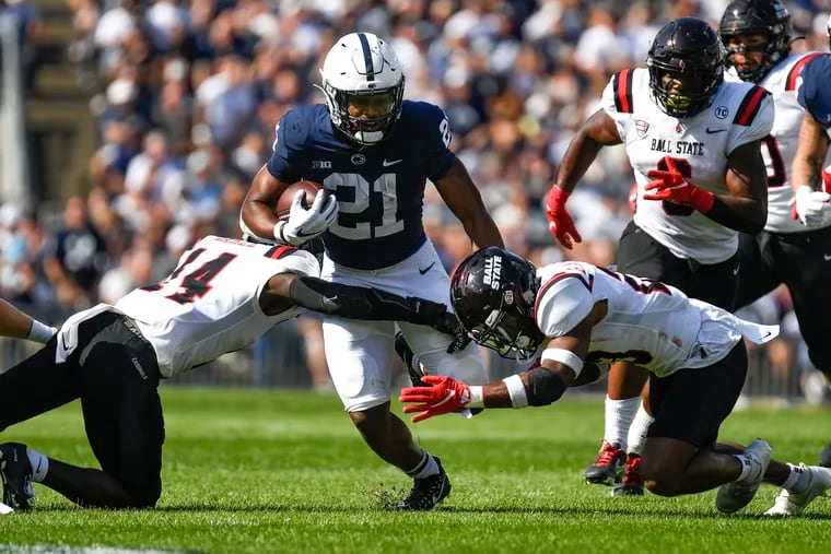 Penn State running back Noah Cain (21) splits two Ball State defenders on a first half run during a game in State College on Sept. 11. Penn State defeated Ball State 44-13