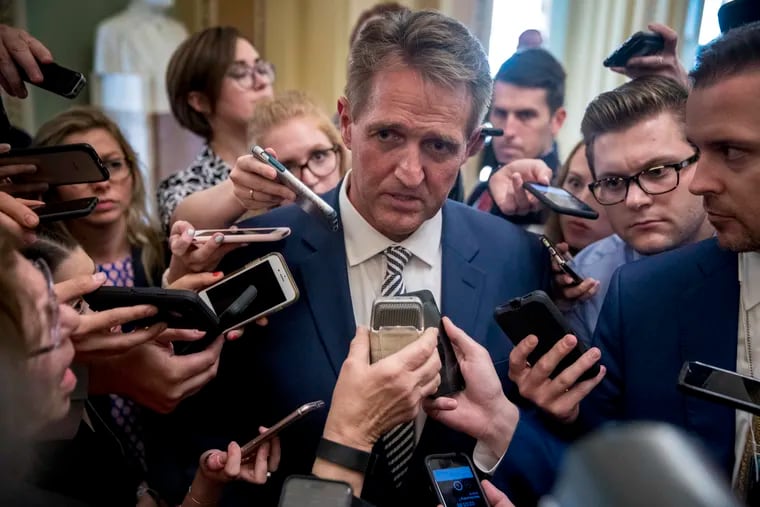 Sen. Jeff Flake, R-Ariz., center, speaks with reporters in Washington, Friday, Sept. 28, 2018. The Senate Judiciary Committee advanced Brett Kavanaugh's nomination for the Supreme Court after agreeing to a late call from Sen. Jeff Flake, R-Ariz., for a one week investigation into sexual assault allegations against the high court nominee.