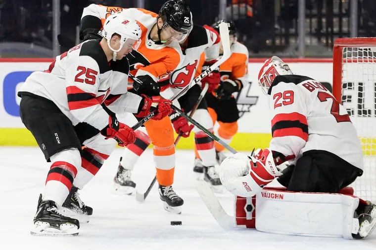 Flyers left winger James van Riemsdyk battles for a loose puck against New Jersey goaltender Mackenzie Blackwood (left) and the Devils' Mirco Mueller (right) during a Feb. 6 game.