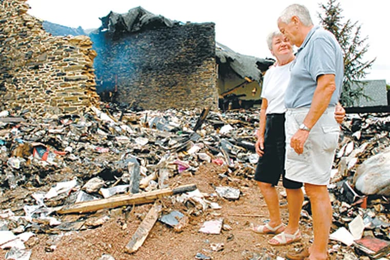 Ben Cavanaugh and his wife, Peg, support each other at the scene of the fire that destroyed their barn and 30,000 books Cavanaugh spent 50 years collecting. (Peter Tobia / Inquirer)