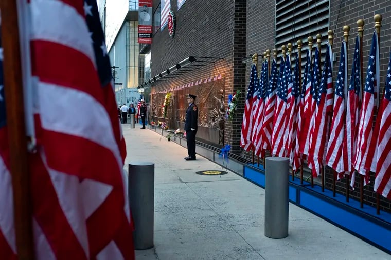 New York City firefighters stand at attention in front of a memorial on the side of a firehouse adjacent to One World Trade Center and the 9/11 Memorial site during ceremonies commemorating the 18th anniversary of the 9/11 terrorist attacks in New York on Wednesday, Sept. 11, 2019.