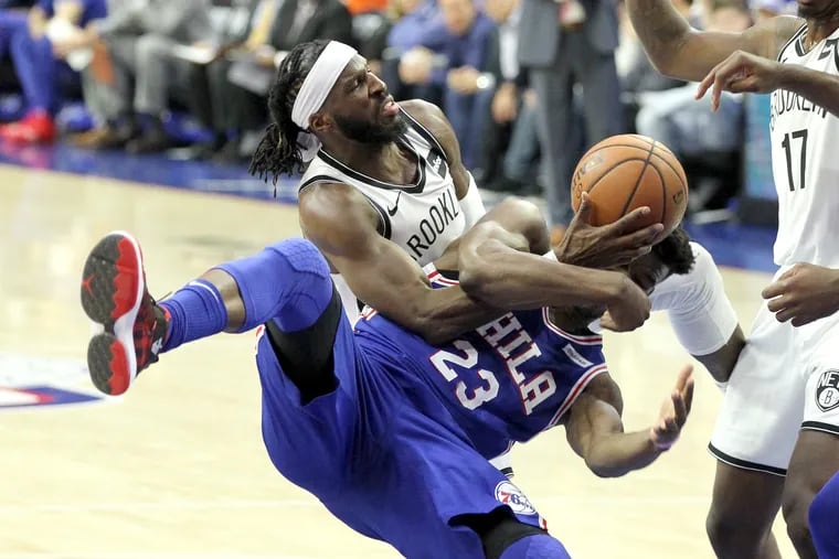Jimmy Butler, bottom, of the Sixers gets roughly fouled by DeMarre Carroll of the Nets during the 1st half of their NBA playoff game at the Wells Fargo Center on April 13, 2019.