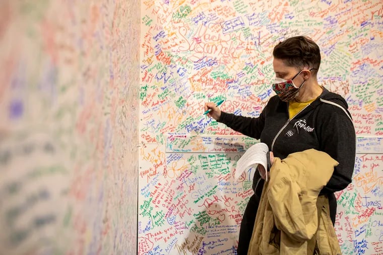 Kathy Balsley, of West Philadelphia, writes her name and thanks the workers on a white board after receiving her vaccination at TLA from Pennsylvania Hospital on Friday, March, 5, 2021.