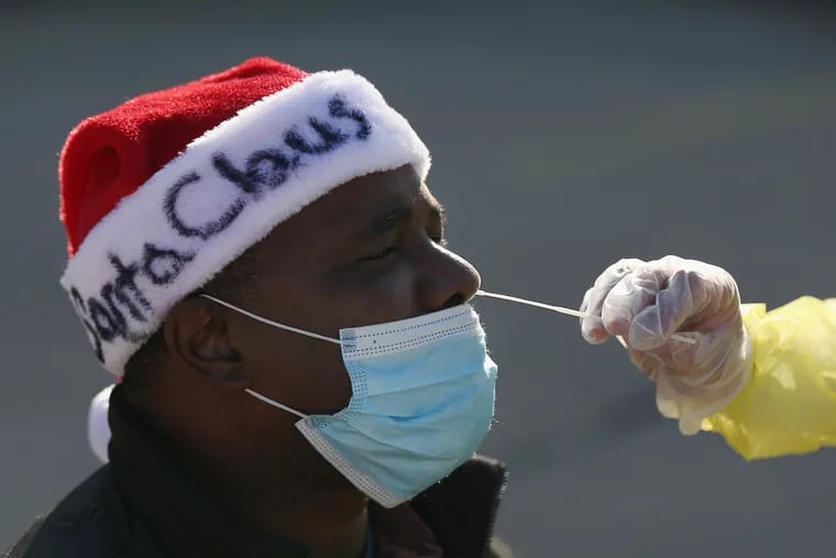 Anthony Harvin wears a Santa hat as he receives a coronavirus test from Dante Terracciano of Philly Fighting COVID at Vine Memorial Baptist Church in West Philadelphia.