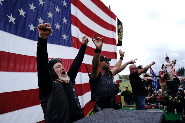 Members of the Proud Boys, including leader Enrique Tarrio, second from left, gesture and cheer on stage as they and other right-wing demonstrators rally in Portland, Ore. During Tuesday night's debate, President Donald Trump didn't condemn white supremacist groups and their role in violence in some American cities this summer. Instead, he said the violence is a “left-wing" problem and he told one far-right extremist group to “stand back and stand by.”