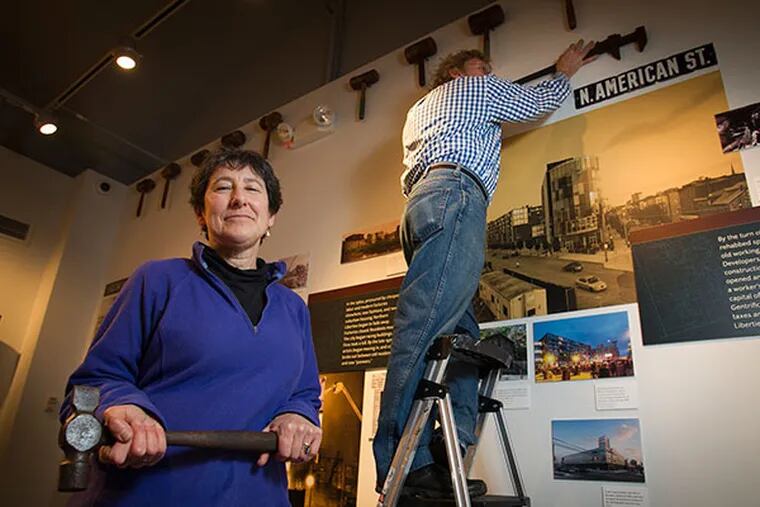 Jennifer Baker, exhibit curator for "Northern Liberties: from Worlds Workshop to Hipster Mecca and People in Between," exhibit at the Philadelphia History Museum in Philadelphia. Randy Dalton assists in hanging the exhibit in the background.  ( ALEJANDRO A. ALVAREZ / STAFF PHOTOGRAPHER )