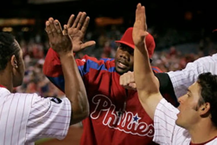 Abraham Nunez (left) is congratulated by teammates (from left) Ryan Howard, Greg Dobbs and Jayson Werth after scoring the final run in the eighth inning of the Phillies&#0039; comeback victory.