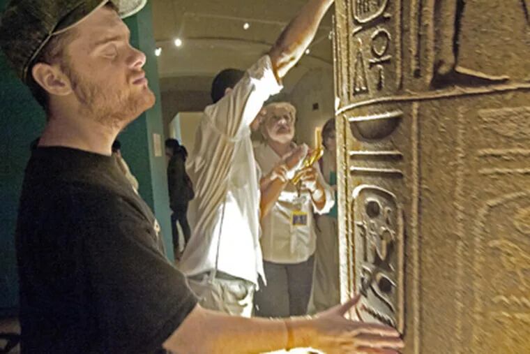Anthony Coughlan, 19, touches hieroglyphs at the Penn Museum of Archaeology and Anthropology's Egyptian exhibits. (April Saul / Staff Photographer)