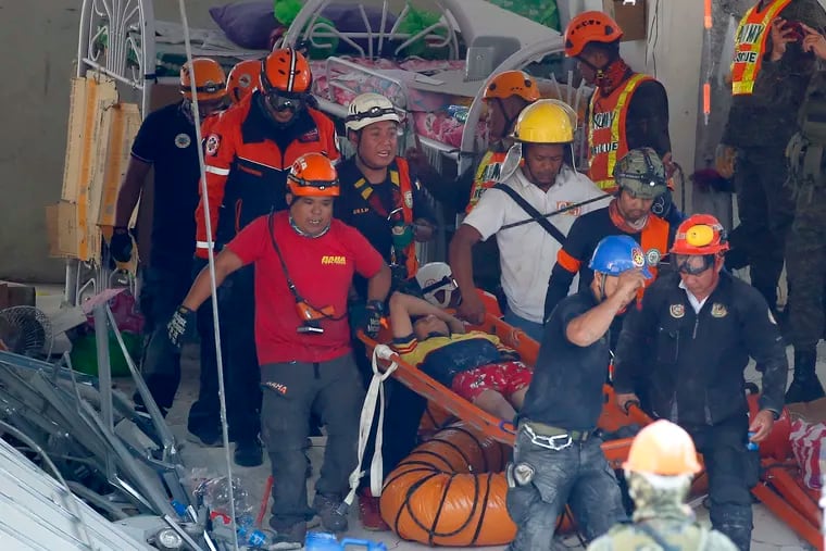 Rescuers carry an earthquake survivor after being pulled out from the rubble of a commercial building following Monday's 6.1 magnitude earthquake in Porac township, Pampanga province, north of Manila, Philippines, Tuesday, April 23, 2019.