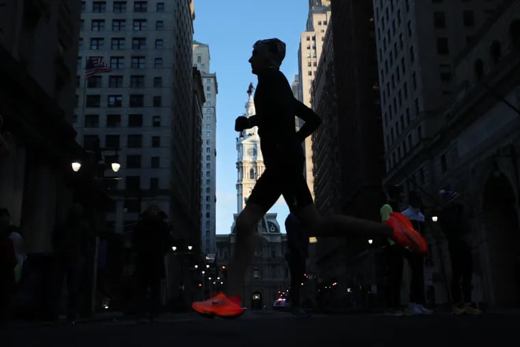 A runner crosses Broad and Walnut streets during the Philadelphia Marathon on Sunday, Nov. 20, 2022.