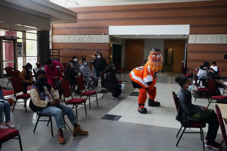 Gritty shakes his hips in front of people waiting to receive COVID-19 vaccines at the Black Doctors COVID-19 Consortium clinic at the Liacouras Center in North Philadelphia on Thursday.