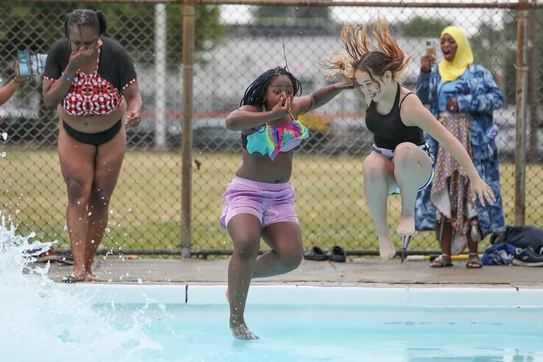 From left, Lisa Kidd, Keyana Mason, and Julianna Cosme jump in together on the first day of the 2023 pool season in Philadelphia. While 60 outdoor pools will open this summer, Philly is home to just one indoor pool, stifling access for residents to have a place to swim year-round.