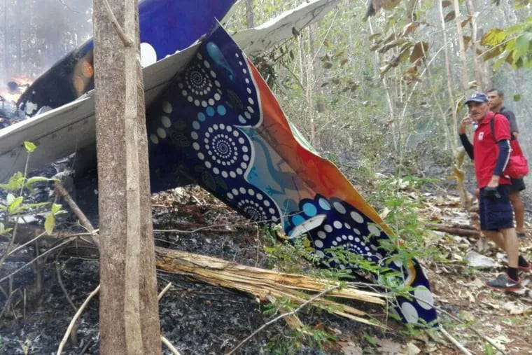 This photo released by Costa Rica’s Public Safety Ministry shows people standing at the site of a plane crash near in Punta Islita, Guanacaste, Costa Rica, Sunday, Dec. 31, 2017. A government statement says there were 10 foreigners and two Costa Rican crew members aboard the plane belonging to Nature Air, which had taken off nearby.
