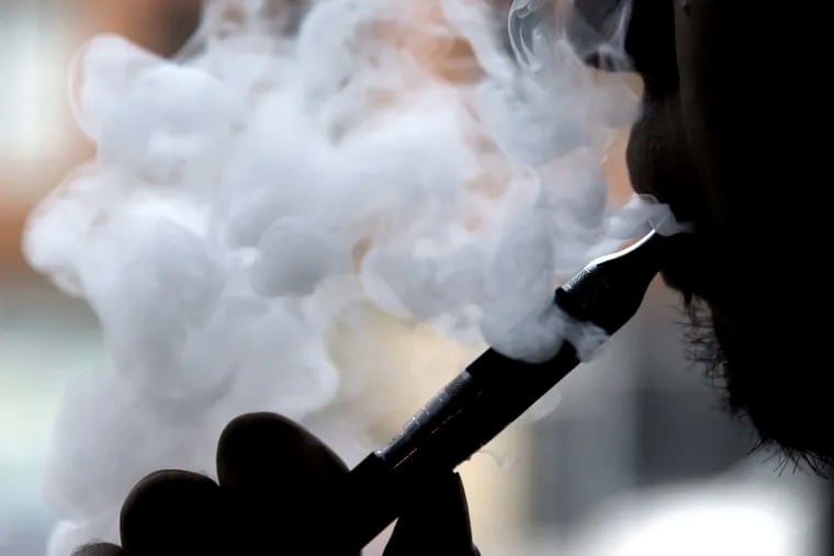 FILE - In this April 23, 2014 file photo, a man smokes an electronic cigarette in Chicago.  The CDC is investigating 215 cases of severe lung illness potentially related to vaping in 25 states.