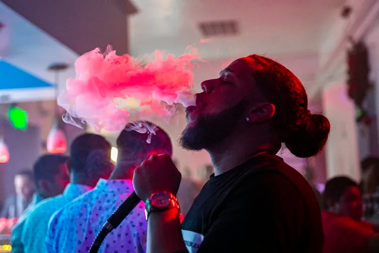 Julio Dinzey, 26, better known as Papeleta -- Spanish for paper bill, has been a hookero for six years. The Dominican native lights a hookah in front of a client at Tierra Nightclub on Saturday, December 7.