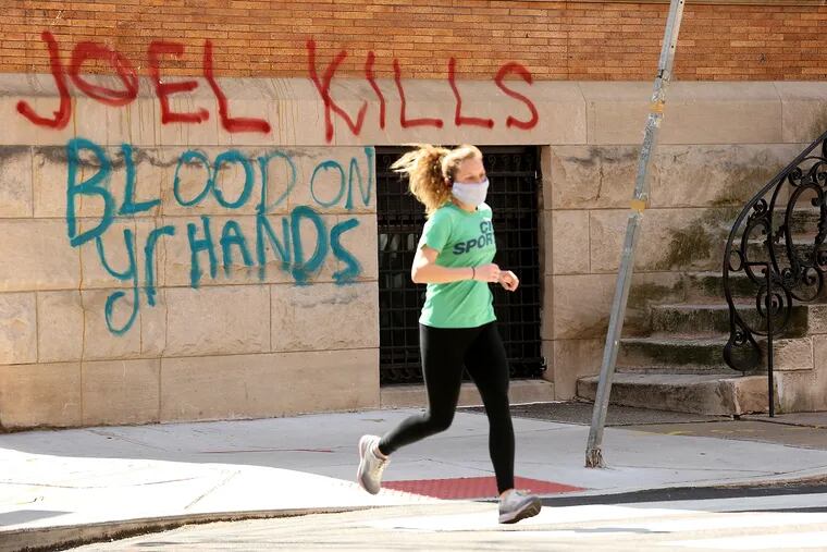 A jogger passes the vandalized home belonging to Joel Freedman.