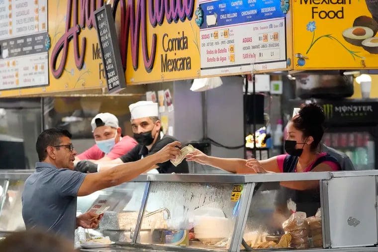 Money being exchanged at a food stand while workers wear face masks inside Grand Central Market on July 13 in Los Angeles.