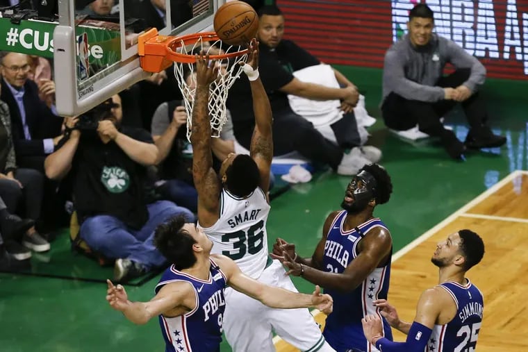 Celtics guard Marcus Smart puts back a miss for a basket past Sixers forward Dario Saric, center Joel Embiid and guard Ben Simmons late in the fourth-quarter in game five of the Eastern Conference semifinals on Wednesday, May 9, 2018 in Boston.