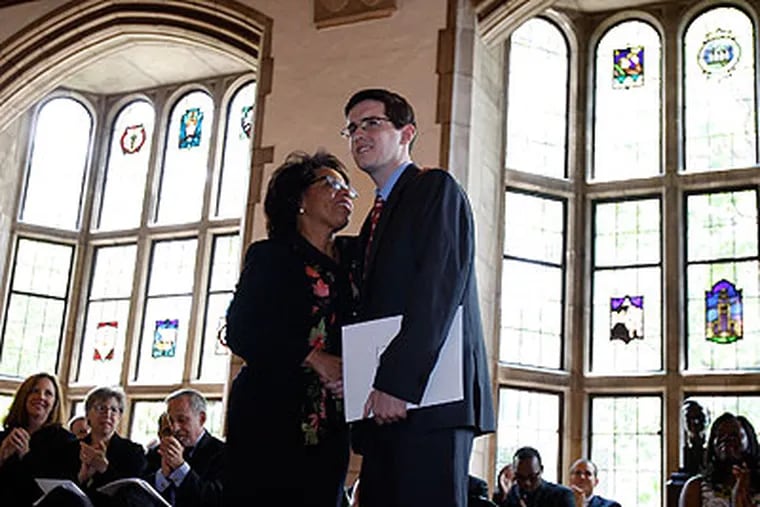 Temple Law School Dean JoAnne Epps, left, hugs Anthony Foltz, a Temple University Law student, after he received the Crossen Award Thursday. The award is given to a graduate who overcame adversity and demonstrated perseverance. Foltz was struck by a car while crossing the Ben Franklin Parkway last year. (David Maialetti / Staff Photographer)