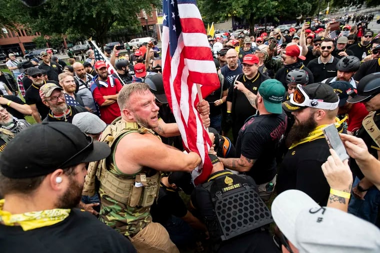 Joseph Oakman and fellow Proud Boys plant a flag in Tom McCall Waterfront Park during an "End Domestic Terrorism" rally in Portland, Ore., on Saturday, Aug. 17, 2019.  Portland Mayor Ted Wheeler said the situation was "potentially dangerous and volatile" but as of early afternoon most of the right-wing groups had left the area via a downtown bridge and police used officers on bikes and in riot gear to keep black clad, helmet and mask-wearing anti-fascist protesters — known as antifa — from following them.