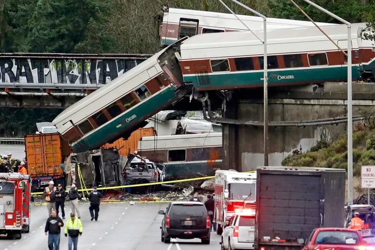 FILE - In this Dec. 18, 2017, file photo, cars from an Amtrak train lay spilled onto Interstate 5 alongside smashed vehicles as some train cars remain on the tracks above in DuPont, Wash. Federal safety investigators are expected to present their findings Tuesday, May 21, 2019, on the Amtrak train derailment south of Seattle that killed three people and injured dozens. (AP Photo/Elaine Thompson, File)