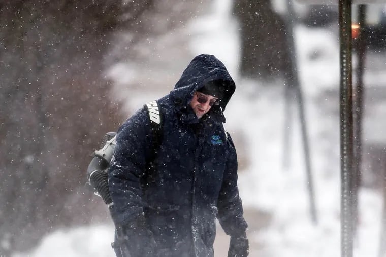 A man shows a leaf-blower to clear away snow after a January 2014 snowfall. After the snow stopped that year, KYW ratings tumbled, evidence of how the weather affects listenership.