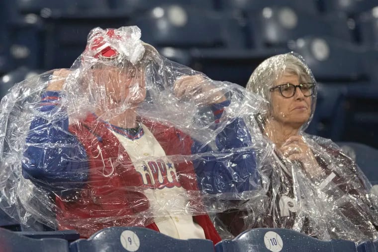 Fans shield from the rain at Citizens Bank Park before Game 3 of the World Series in October.