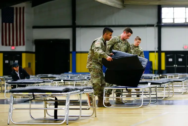 Members of the 103rd Brigade Engineer Battalion National Guard put together cot beds in the gymnasium at the Glen Mills School on Saturday. FEMA and National Guard members will assemble medical equipment and beds in the field hospital to make room for coronavirus patients elsewhere.