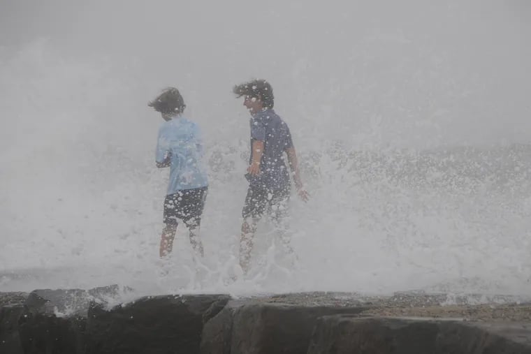 Jack Fleming (left) and his friend Tommy Goldstein, both of Radnor, turn from the waves splashing against the breakwater on the causeway and bridge across Townsend's Inlet between Avalon and Sea Isle on July 10 when Tropical Storm Fay was breezing by.