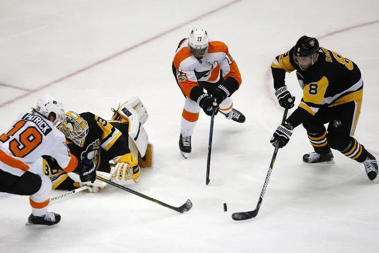Pittsburgh’s Brian Dumoulin clears the puck from in front of goalie Matt Murray before the Flyers’ Wayne Simmonds and Nolan Patrick can get their sticks on it during the first period of Monday night’s 5-4 overtime loss.