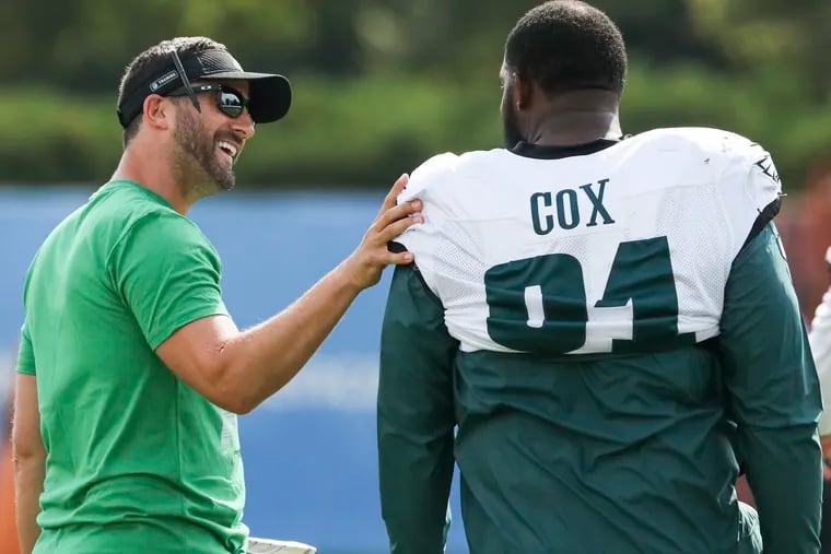 Eagles head coach Nick Sirianni greeting defensive tackle Fletcher Cox  while he warms up during training camp at the NovaCare Complex.