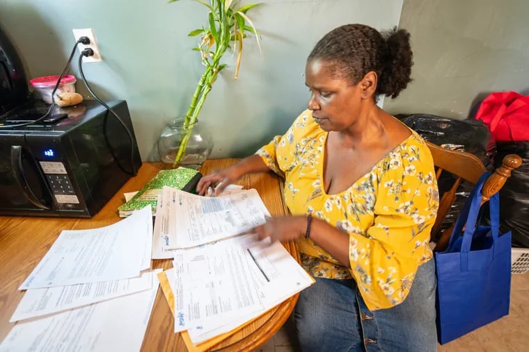 Janell Johnson-Washington looks through previous energy bills at her home on Thursday, June 29, 2023.   Johnson-Washington says that unbeknownst to her after speaking with salespeople at her door, her electricity provider was switched from PECO to StateWise Energy, which resulted in bills that were far higher.