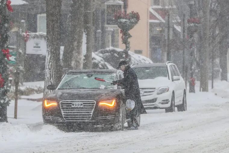 A motorists brushes the snow off his windshield before attempting to drive in the snow on Thursday, Jan. 4, 2018.