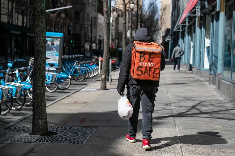A food delivery worker who did not want to give his name has "Be Safe" written on his delivery backpack while walking down Chestnut Street in March.