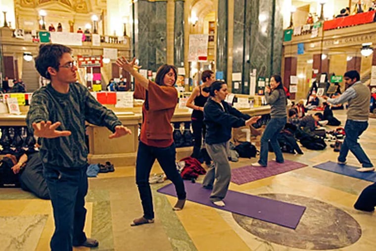 Protesters do yoga inside the state Capitol Tuesday, Feb. 22, 2011, in Madison, Wis. Opponents to Governor Scott Walker's bill to eliminate collective bargaining rights for many state workers are taking part in their eighth day of protesting. (AP Photo/Jeffrey Phelps)
