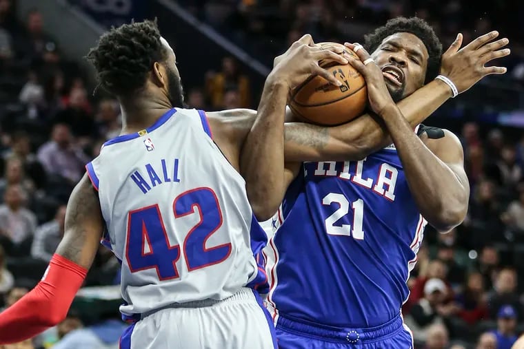 The Sixers' Joel Embiid gets tangled with the Pistons' Donta Hall.