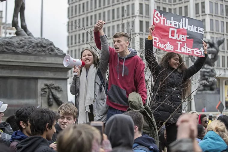 Olivia Sandom, left, 17, of Masterman and Bryan McCurdy, right, 18, of the Academy at Palumbo lead the crowd in a chant — Hold hands not guns — during the student walkout at City Hall on March 14. A subsequent rally for gun control is scheduled for Saturday.